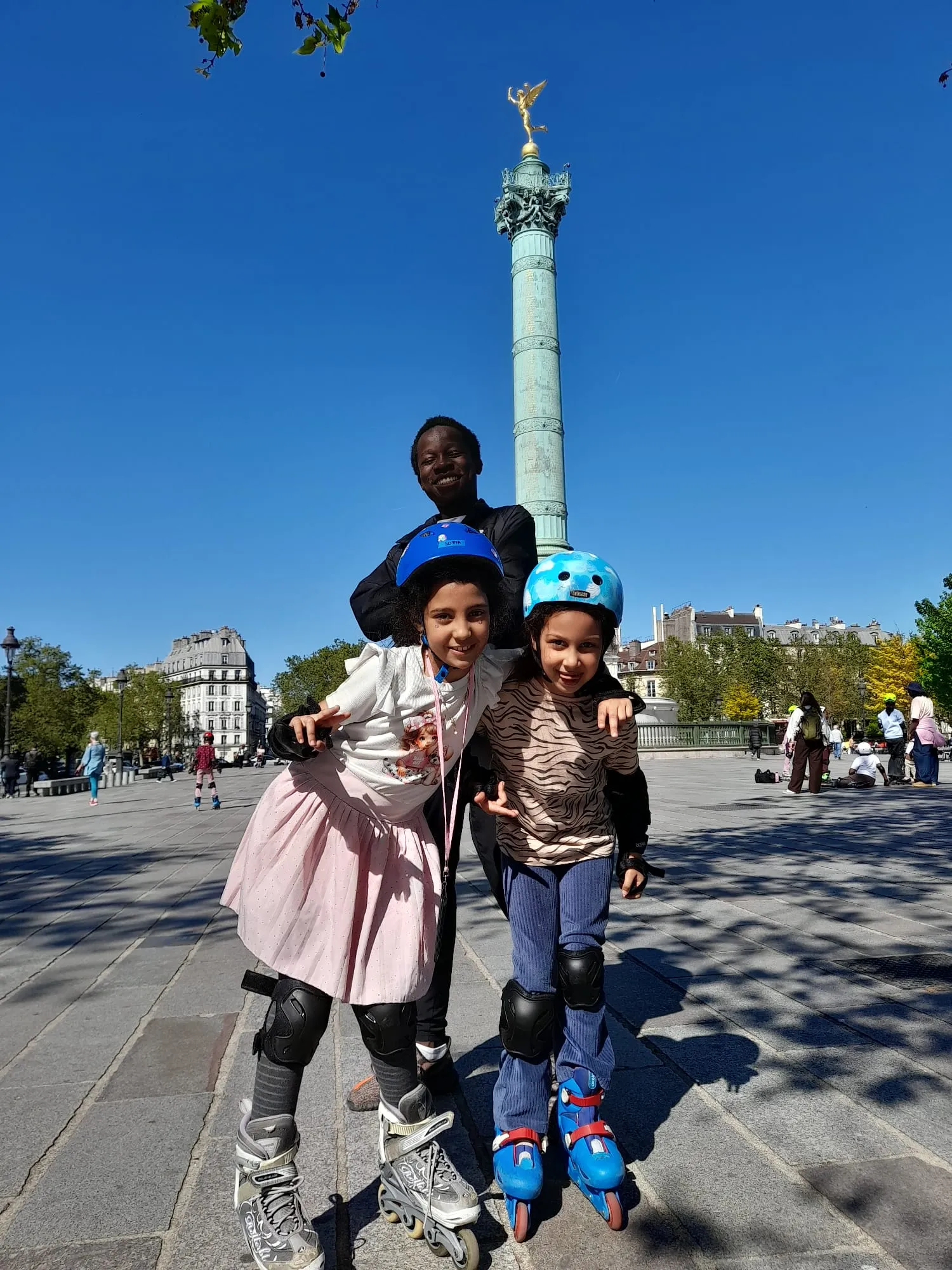 Deux enfants en rollers, casque et protections, avec leur animateur place de la Bastille à Paris